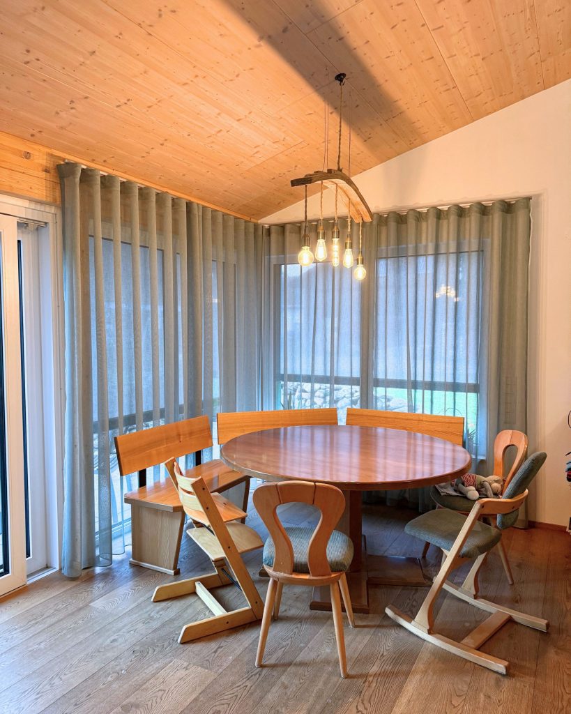 Essbereich mit maßgefertigten Vorhängen aus dem Stoff ‚Maran‘ von A House of Happiness im Farbton Salbei, genäht und montiert von Die Raumausstatterin im Allgäu.
