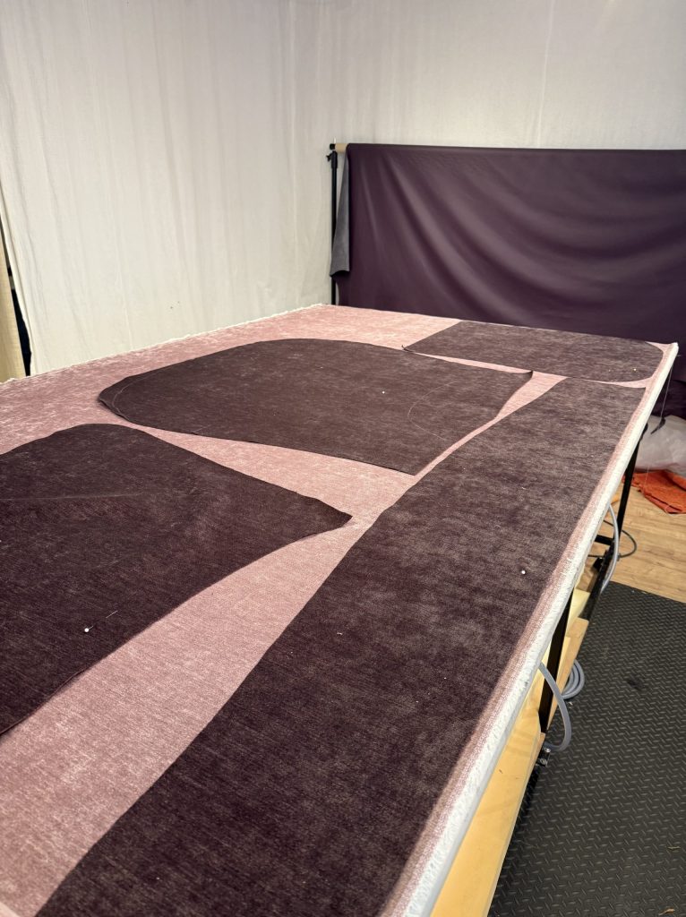 Zugeschnittene Stoffteile liegen auf einem großen Arbeitstisch in der Werkstatt