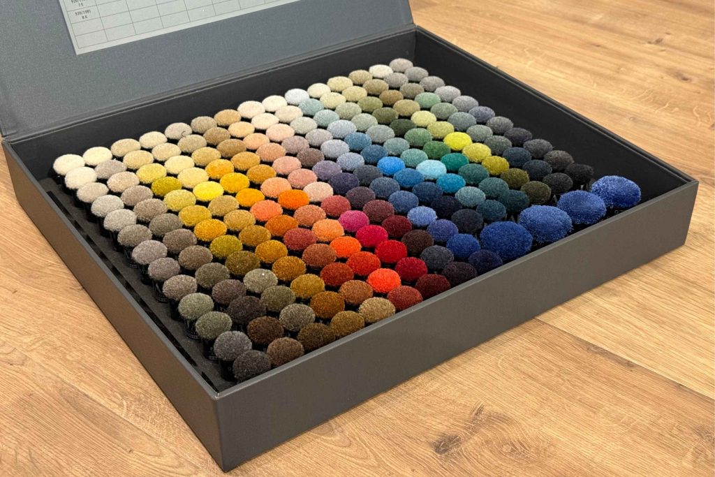 Übersichtlich angeordneter Musterkoffer mit vielen Farb- und Materialvarianten als Grundlage für eine strukturierte Teppichberatung.