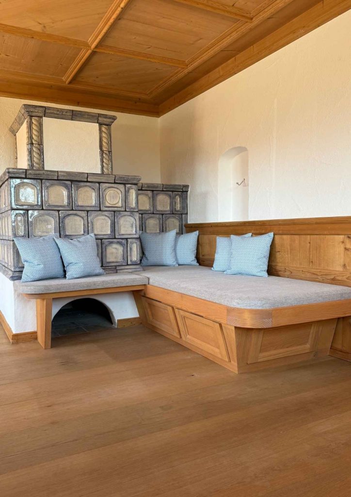 Eckbank aus Holz mit maßgefertigten hellen Sitzpolstern und gemusterten Kissen