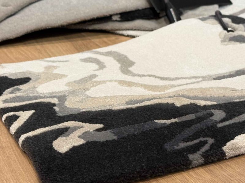 Getuftete Teppichmuster in unterschiedlichen Materialien, Florhöhen und Farbnuancen, ausgelegt zum Vergleich von Struktur und Wirkung im Raum