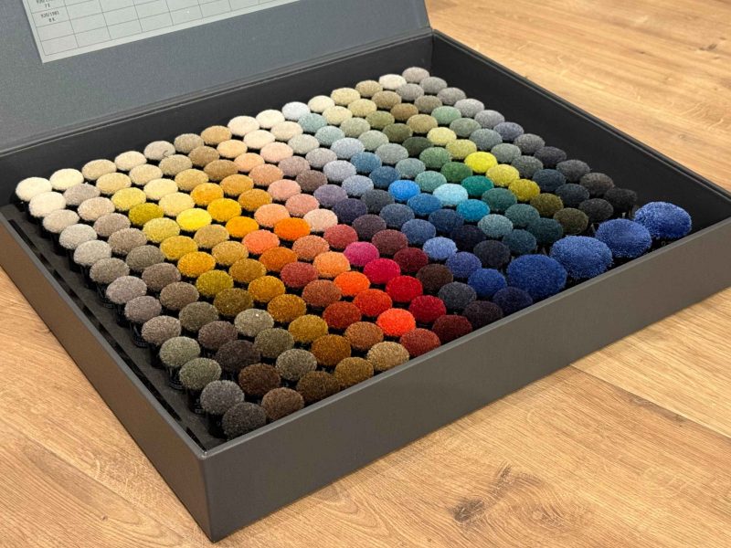 Übersichtlich angeordneter Musterkoffer mit vielen Farb- und Materialvarianten als Grundlage für eine strukturierte Teppichberatung.