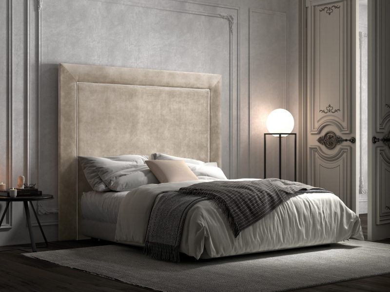 Polstermöbel Bettkopfteil Renia aus der DMG Kollektion in schlichtem, geradlinigem Design. Kombiniert mit einem Bett in opulent-romantischem Ambiente: Stuckkasetten an Wänden und Decke, moderne Lampe mit kugelförmigem Leuchtkörper, kleiner Beistelltisch als Nachtkästchen sowie leger arrangiertes Bettzeug mit Plaid