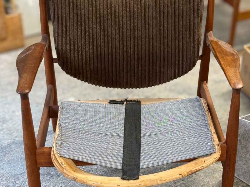 Finn Juhl 136 Sessel mit altem braunen Cordbezug auf der Rückenlehne und zerfallener Sitzfläche mit Flächengurt, Zustand bei Anlieferung in der Werkstatt