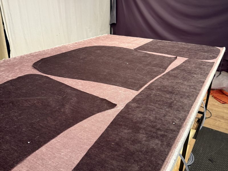 Zugeschnittene Stoffteile liegen auf einem großen Arbeitstisch in der Werkstatt